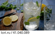Pouring soda water from a decanter with ice lemon and mint. Making lemonade. Стоковое видео, видеограф Алексей Гекало / Фотобанк Лори