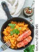 Stewed cabbage with carrots, onions and tomatoes and sausages in bacon with parsley and spices in a cast iron pan. Bigos. Delicious lunch. Стоковое фото, фотограф Виктория Панченко / Фотобанк Лори