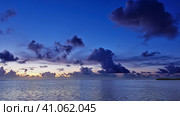 The sun disappeared over the horizon. In the evening sky, orange illumination and purple cumulus clouds. Reflection on the ocean surface. Maldives. Стоковое фото, фотограф Вера Ивановна Кубарева / Фотобанк Лори