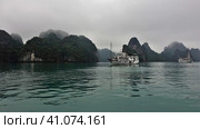 Quaint islands with steep slopes hide in the fog. There are tourist ships on the smooth water of the bay. Halong Bay. Vietnam. Стоковое фото, фотограф Вера Ивановна Кубарева / Фотобанк Лори