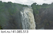 The Zambezi River flows from the edge of the plateau into the gorge, forming Victoria Falls. There is lush green vegetation around. The fog hangs over the abyss. Zimbabwe (2020 год). Стоковое фото, фотограф Вера Ивановна Кубарева / Фотобанк Лори