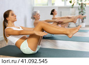 Three generation of women perform sitting lightweight variation of boat pose Paripurna Navasana. Стоковое фото, фотограф Яков Филимонов / Фотобанк Лори