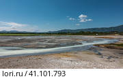 Thermal streams flow in the caldera of an extinct volcano. Blue opaque water. Sulphurous deposits are visible on the soil. A mountain range against the blue sky in the distance. Kamchatka. Uzon. Стоковое фото, фотограф Вера Ивановна Кубарева / Фотобанк Лори