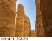Colonnade in the hypostyle hall of the Karnak Temple of Luxor. Hieroglyphs and carvings are visible on the columns. The background is blue sky. Close-up. Egypt (2021 год). Стоковое фото, фотограф Вера Ивановна Кубарева / Фотобанк Лори