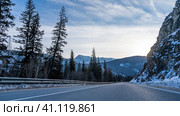 The highway runs along a steep mountain. Snow on a rocky slope. Metal protective barrier on the side of the road. Coniferous trees and a mountain range against the sky. Altai. Chuysky tract. Стоковое фото, фотограф Вера Ивановна Кубарева / Фотобанк Лори