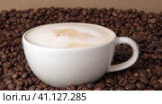 Drop of milk falling in a white cup with black coffee. Side View. Slow Motion. Coffee droplet. Roasted coffee beans background. Freshly brewed latte cappuccino. Close up. Coffee product advertising. Стоковое видео, видеограф Марина Демидюк / Фотобанк Лори