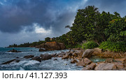 Evening on a tropical island. Boulders lie near the shore of the turquoise ocean. Waves are foaming on the rocks. Lush tropical vegetation against the sky and clouds. Seychelles. Mahe. Стоковое фото, фотограф Вера Ивановна Кубарева / Фотобанк Лори