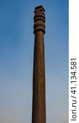 The famous ancient iron pillar, not subject to corrosion, against the blue sky. The top of the column is decorated with cast ornaments. India. Qutub Minar Temple complex. Delhi. (2022 год). Стоковое фото, фотограф Вера Ивановна Кубарева / Фотобанк Лори