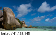 Picturesque granite rocks with smoothed folded steep slopes are on the beach of a tropical island. The turquoise ocean is calm. Clouds in the blue sky. Seychelles. La Digue. Anse Source D’Argent. Стоковое фото, фотограф Вера Ивановна Кубарева / Фотобанк Лори