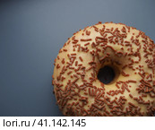 A doughnut or donut. A type of leavened fried dough. Sweet snack that can be homemade or purchased in bakeries, supermarkets, food stalls. Delicious pie with light icing on a dark gray background. Стоковое фото, фотограф Юлия Петровская / Фотобанк Лори