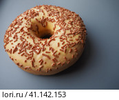 A doughnut or donut. A type of leavened fried dough. Sweet snack that can be homemade or purchased in bakeries, supermarkets, food stalls. Delicious pie with light icing on a dark gray background. Стоковое фото, фотограф Юлия Петровская / Фотобанк Лори