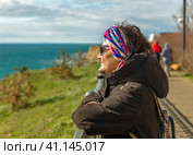 Portrait of a woman in a jacket standing on the embankment and looking at the sea    портрет Женщины в куртке стоящей на набережной и смотрящей на море. Стоковое фото, фотограф Владимир Ушаров / Фотобанк Лори