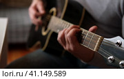 Playing the guitar. Strumming acoustic guitar. Musician plays music. Man fingers holding mediator. Man hand playing guitar neck in dark room. Unrecognizable person rehearsing, fretboard close-up. Стоковое видео, видеограф Марина Демидюк / Фотобанк Лори