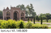 The red sandstone building in the complex of the tomb of Itmad-Ud-Daulah. Arched entrance, white decorative ornaments on the walls. Green vegetation around. India. Agra (2022 год). Стоковое фото, фотограф Вера Ивановна Кубарева / Фотобанк Лори