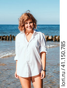 Young blonde woman in a white swimsuit and shirt posing standing on the seashore. Стоковое фото, фотограф Радомир Тарасов / Фотобанк Лори