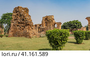 Ruins of the ancient temple complex Qutub Minar. Dilapidated brick walls of buildings with arches. Around, on green lawns - trimmed bushes, trees. Blue sky. India. Delhi. (2022 год). Стоковое фото, фотограф Вера Ивановна Кубарева / Фотобанк Лори