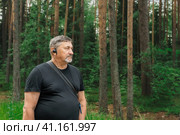 Portrait of a man in his 70s with a radio guide earpiece in the woods. Travelling pensioners. Konevets Island, Karelia, Ladoga Lake. Стоковое фото, фотограф Оксана Медведева / Фотобанк Лори