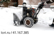 Snowblower removes snow, a man cleans the yard outside. Стоковое фото, фотограф Igor Skripachev / Фотобанк Лори