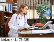 Young woman doctor filling up medical forms on laptop in office. Стоковое фото, фотограф Яков Филимонов / Фотобанк Лори