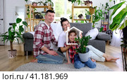 Traditional family with child are enjoying new home, sitting on the sofa and holding the roof. Mortgage, insurance and protection, buying and moving into your own home, green house with potted plant. Стоковое видео, видеограф Ольга Симонова / Фотобанк Лори