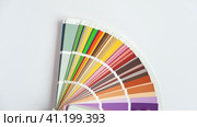 Female Hand opening Color guide close up. Assortment of Colour samples for design. Colors palette fan on white concrete wall background. Graphic designer chooses colors. Coloured swatches catalogue 4K. Стоковое видео, видеограф Марина Демидюк / Фотобанк Лори
