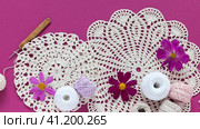Video of summer needlework and craft. Two round handmade lace napkins, skeins of cotton yarn, crochet hooks and cosmea flowers on pink background. DIY concept. Top view, close up, flat lay. Стоковое видео, видеограф Виктория Катьянова / Фотобанк Лори