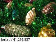 Multi-colored glass cones on green Christmas tree tinsel. Beautiful Christmas toys and decorations as a background. Red, yellow, green and pink shiny new year and christmas figurines. Стоковое фото, фотограф Юлия Петровская / Фотобанк Лори