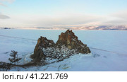 View of Shamanka Rock or Cape Burkhan in winter. Frozen Lake Baikal in the snow. Aerial view. Вид на скалу Шаманка или мыс Бурхан зимой. Замерзшее озеро Байкал в снегу. Стоковое видео, видеограф Виктория Тельминова / Фотобанк Лори