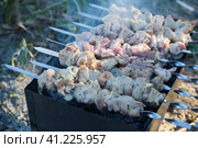 Photo of pork kebab, which is fried on the grill in a camp at sunset. Smoke rises from the grill. Focus on the middle plan. фотография свиного шашлыка, который жарят на гриле в лагере на закате. От гриля поднимается дым. Фокус на средней плоскости. Стоковое фото, фотограф Дмитрий Березнев / Фотобанк Лори