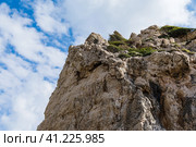 Mediterranean Cyprus rock against blue cloudy sky. Some green grow on the rock. View from the beach. Средиземноморская скала Кипра на фоне голубого облачного неба. На скале растет какая-то зелень. Вид с пляжа. (2019 год). Стоковое фото, фотограф Дмитрий Березнев / Фотобанк Лори