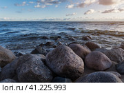 Sunset photo of the stones on the shoreline of the finnish bay in St. Petersburg. Rocks located on the beach. against the background of a choppy sea and a cloudy sky. Фотография камней на берегу Финского залива на закате в Санкт-Петербурге. Скалы, расположенные на пляже. на фоне неспокойного моря и облачного неба. Стоковое фото, фотограф Дмитрий Березнев / Фотобанк Лори