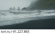 The black sand beach of Reynisfjara with waves hitting the shore on foggy rainy stormy day Vik, Iceland. Стоковое фото, фотограф Igor Tichonow / Фотобанк Лори
