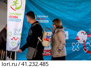 Люди записываются на прием в мобильный пункт бесплатной вакцинации от гриппа в специальном автомобиле скорой помощи у метро в городе Москве, Россия (2023 год). Редакционное фото, фотограф Николай Винокуров / Фотобанк Лори