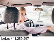 Female driver looking back while reversing in car. Стоковое фото, фотограф Matej Kastelic / Фотобанк Лори