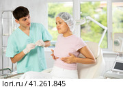 Young male doctor consulting female client on breast augmentation. Стоковое фото, фотограф Яков Филимонов / Фотобанк Лори