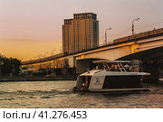 River boat with tourists in front of Nagatinsky Bridge with railroad and trains in Moscow during sunset. Редакционное фото, фотограф Константин Григорьев / Фотобанк Лори