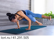 side crow pose variation parsva bacasana yoga with ukrainian woman making it indoors. Стоковое фото, фотограф Татьяна Терехина / Фотобанк Лори