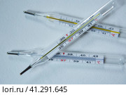 Three classic mercury thermometers with a scale of degrees Celsius lie on a clean white background. Concept of recovery from infection and coronavirus. Стоковое фото, фотограф Наталия Кирсанова / Фотобанк Лори