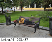 Moscow, Russia, July 11, 2023: Homeless dirty man sleeps on bench in city center. Редакционное фото, фотограф Алексей Антипов / Фотобанк Лори
