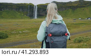 Woman with backpack enjoying impressive Seljalandsfoss waterfall in Iceland. Стоковое видео, видеограф Igor Tichonow / Фотобанк Лори