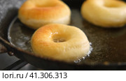 Frying process homemade and delicious donuts on fresh oil in a pan. Blue sugar topping on donuts in a home candy workshop. Pastry, sweet. Making dessert being deep fried. Preparation of donuts. Стоковое видео, видеограф Марина Демидюк / Фотобанк Лори