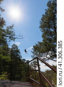 Tourist is going down the ropes - a bungee cable - from a mountain waterfall above the wooded gorge of the Kyngarga River. Fun active summer holiday. Siberia. Buryatia. Arshan resort. Стоковое фото, фотограф Виктория Катьянова / Фотобанк Лори