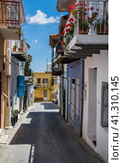 One of the central streets of Lefkara. Very narrow and authentic street. Cozy houses with colorful facades and balconies, decorated with flowers. Одна из центральных улиц Лефкары. Очень узкая и аутентичная улица. Уютные домики с красочными фасадами и балконами, украшенными цветами (2019 год). Стоковое фото, фотограф Дмитрий Березнев / Фотобанк Лори