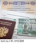 Государственный сертификат материнский (семейный) капитал, договор купли-продажи недвижимости (квартиры), российский паспорт и деньги (2023 год). Редакционное фото, фотограф Цибаев Алексей / Фотобанк Лори