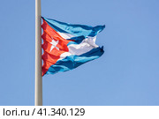 Флаг Республики Куба, островного государства в Латинской Америке, на фоне голубого неба (2019 год). Стоковое фото, фотограф Николай Белецкий / Фотобанк Лори