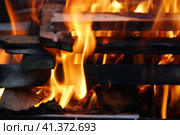 Огонь полыхает между дровами, сложенными друг на друга. Несколько сосновых и березовых поленьев сложены в квадратную башню, в центре которой ярко горят дрова и щепа. Стоковое фото, фотограф Andrew_Swarga / Фотобанк Лори