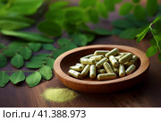 Wooden bowl of moringa capsules and fresh leaves on the table. Superfood, dietary supplement. AI generated. Стоковое AI-изображение, AI-художник Александра Селина / Фотобанк Лори