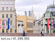 Москва, Россия, сентябрь 2023 года. На Большом Москворецком мосту два человека идут в разные стороны на фоне красивых московских строений разнообразных стилей. На мосту размещены флаги в честь празднования дня города. Редакционное фото, фотограф Сергей Никифоров-Гордеев / Фотобанк Лори