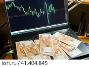 Купюры по пять тысяч рублей лежат на клавиатуре ноутбука с графиком котировок на мониторе. Стоковое фото, фотограф Владимир Шибаев / Фотобанк Лори