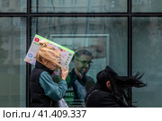 Женщины идут с покупками в ветренную погоду по улице в центре города Москвы (2023 год). Редакционное фото, фотограф Николай Винокуров / Фотобанк Лори